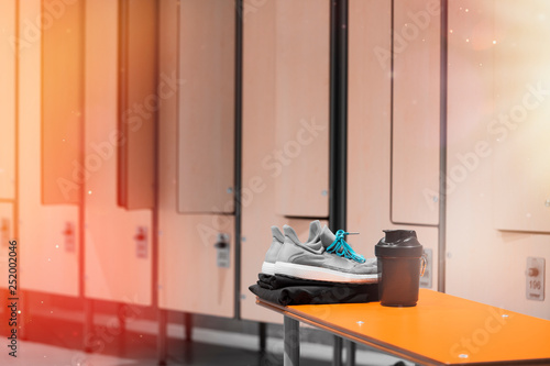 Close up of sports shoes, sportswear and sport water bottle in gym locker room.