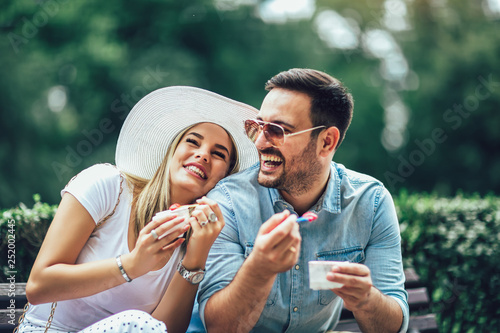 Couple joking and having fun while eating an ice cream in the park.