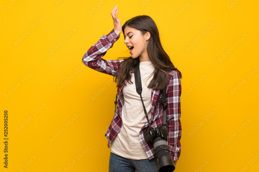 Photographer teenager girl over yellow wall has realized something and intending the solution Photographer teenager girl over yellow wall has realized something and intending the solution
