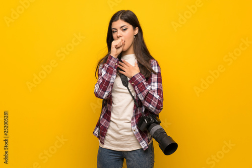 Photographer teenager girl over yellow wall is suffering with cough and feeling bad