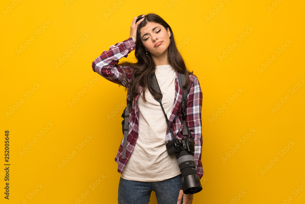 Photographer teenager girl over yellow wall with an expression of frustration and not understanding Photographer teenager girl over yellow wall with an expression of frustration and not understanding