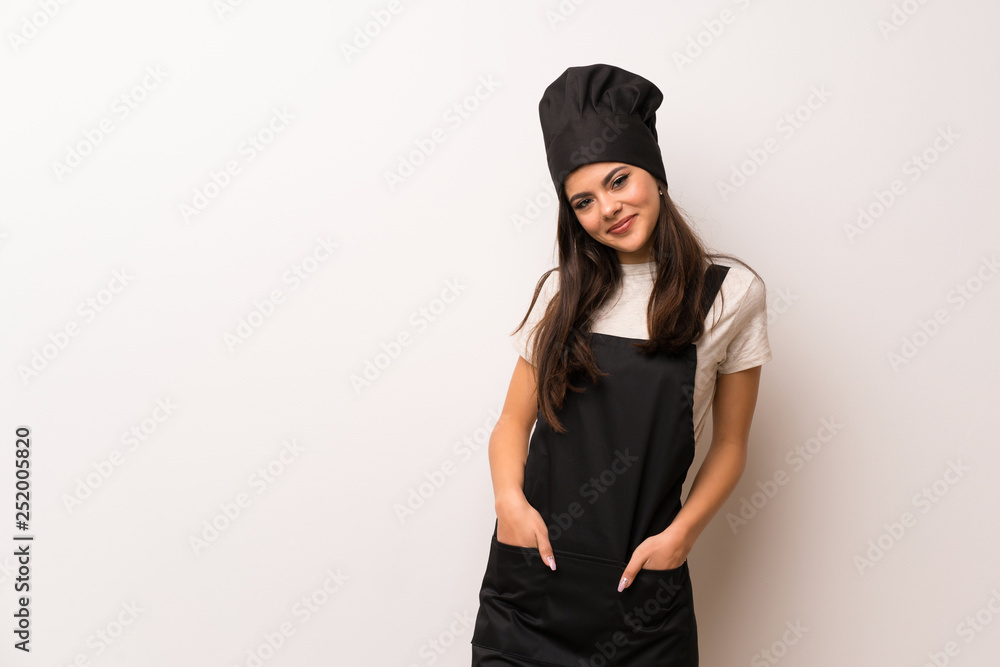 Teenager chef over white wall laughing looking to the front Teenager chef over white wall laughing looking to the front