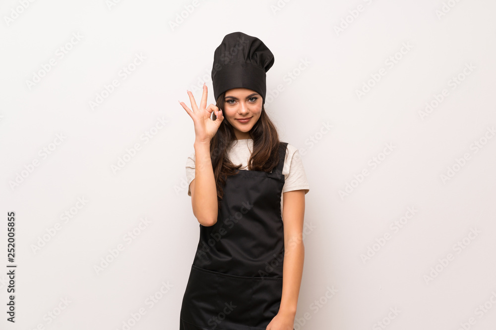 Teenager chef over white wall showing ok sign with fingers Teenager chef over white wall showing ok sign with fingers