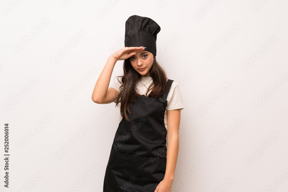Teenager chef over white wall looking far away with hand to look something Teenager chef over white wall looking far away with hand to look something