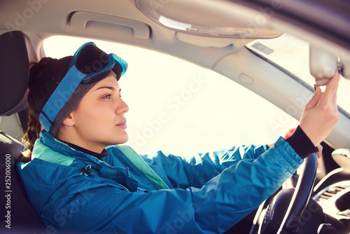 girl driving a car while preparing for skiing on a snowy mountain