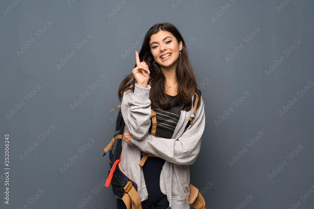 Teenager traveler girl over wall pointing with the index finger a great idea Teenager traveler girl over wall pointing with the index finger a great idea