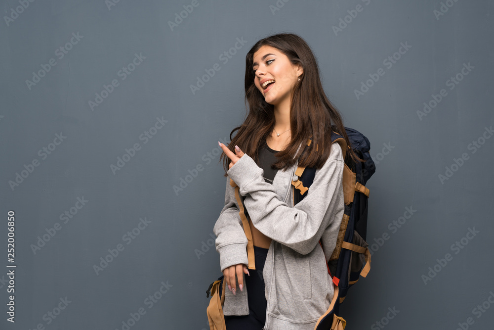 Teenager traveler girl over wall pointing back Teenager traveler girl over wall pointing back