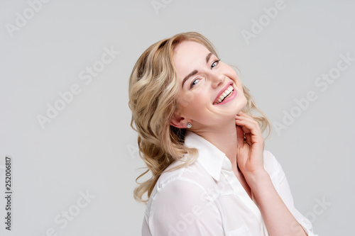 Portrait of smiling curly blonde in white shirt.