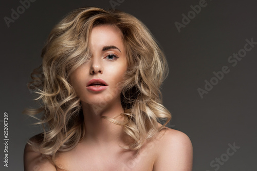 Photo of blonde with curly hair, with bare shoulders.