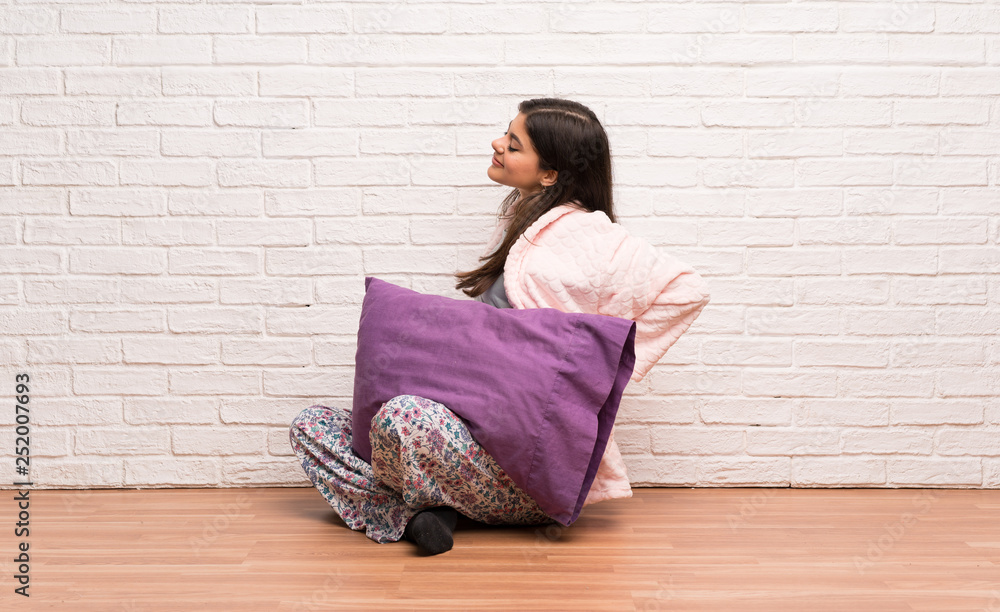 Teenager girl in pajamas suffering from backache for having made an effort Teenager girl in pajamas suffering from backache for having made an effort