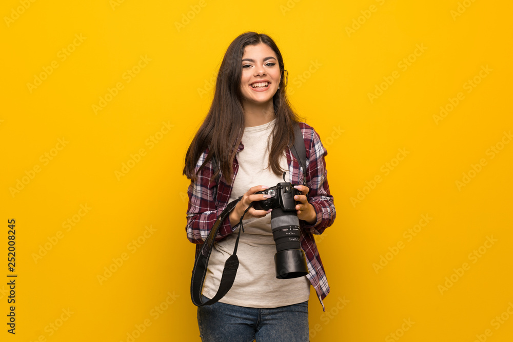 Photographer teenager girl over yellow wall Photographer teenager girl over yellow wall