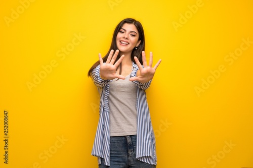 Teenager girl over yellow wall counting ten with fingers