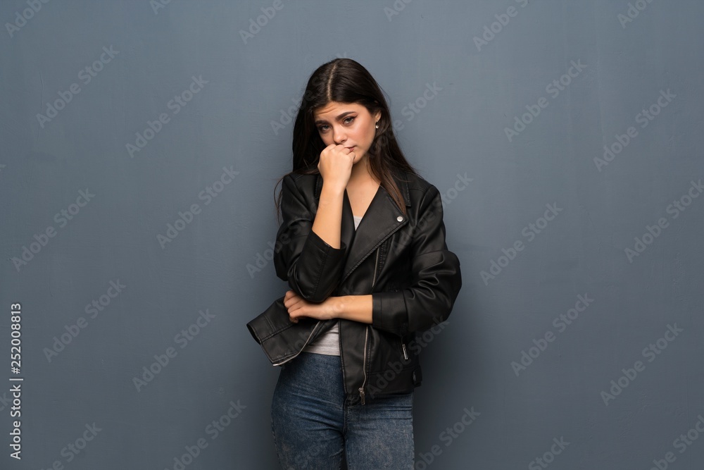 Teenager girl over grey wall having doubts Teenager girl over grey wall having doubts