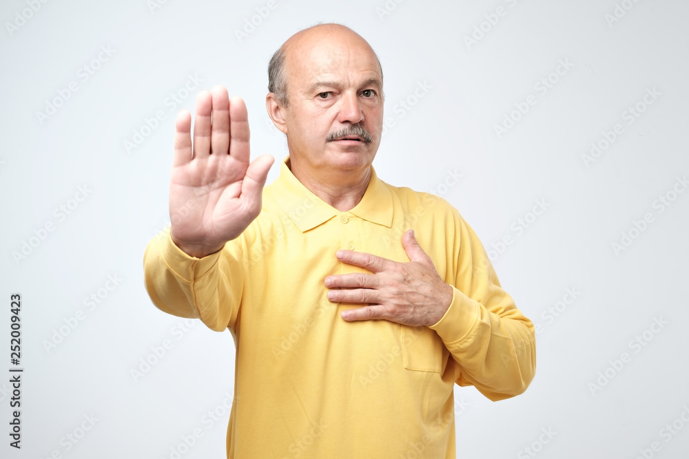 Portrait of a serious senior man showing stop gesture with his palm Portrait of a serious senior man showing stop gesture with his palm