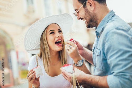 Smiling couple in shopping with ice-cream and shopping bags