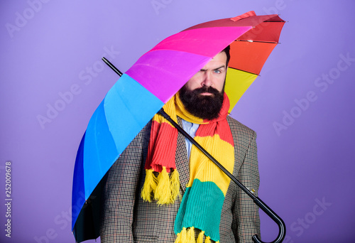 Man bearded hipster hold colorful umbrella. It seems to be raining. Rainy days can be tough to get through. Prepared for rainy day. Carefree and positive. Enjoy rainy day. Weather forecast concept