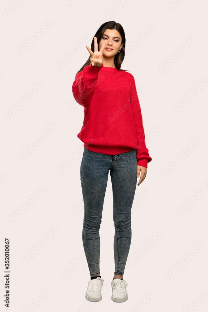A full-length shot of a Teenager girl with red sweater happy and counting three with fingers over isolated background A full-length shot of a Teenager girl with red sweater happy and counting three with fingers over isolated background