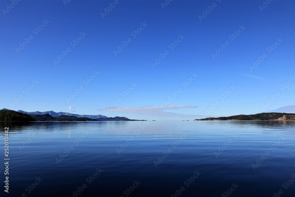 Reflection of blue sky in calm blue water.