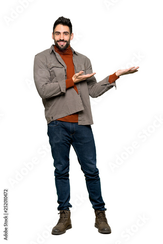 Full-length shot of Handsome man with beard extending hands to the side for inviting to come on isolated white background
