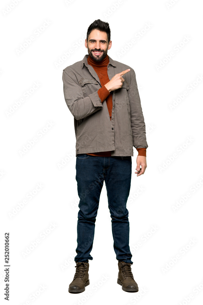 Fototapeta premium Full-length shot of Handsome man with beard pointing to the side to present a product on isolated white background