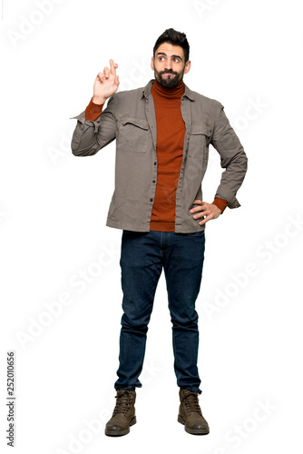Full-length shot of Handsome man with beard with fingers crossing and wishing the best on isolated white background
