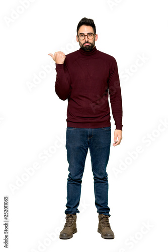 Full-length shot of Handsome man with glasses unhappy and pointing to the side on isolated white background