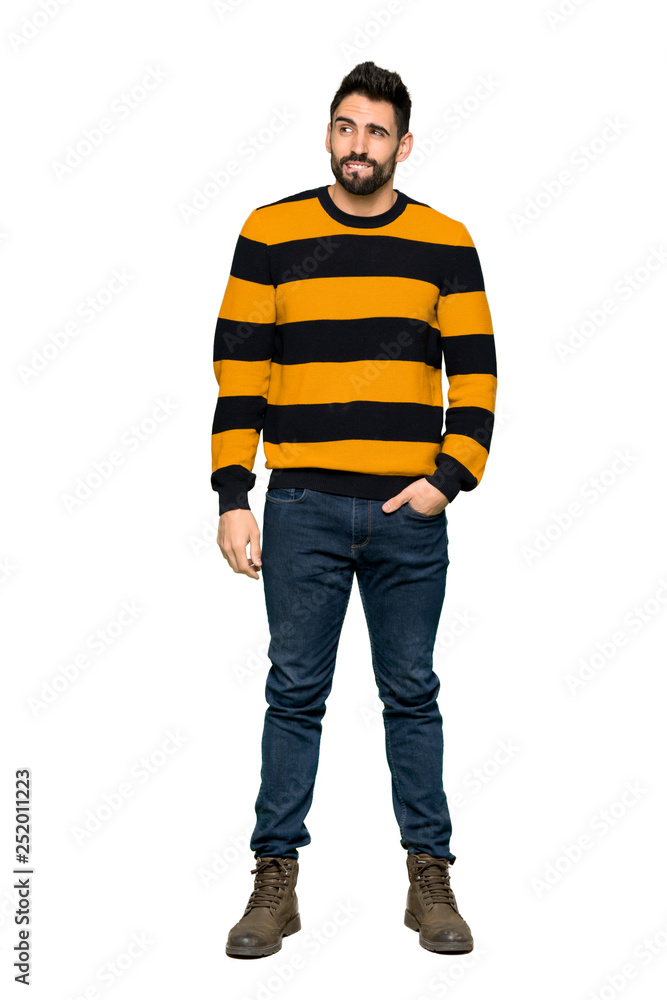 Full-length shot of Handsome man with striped sweater with confuse face expression while bites lip on isolated white background Full-length shot of Handsome man with striped sweater with confuse face expression while bites lip on isolated white background