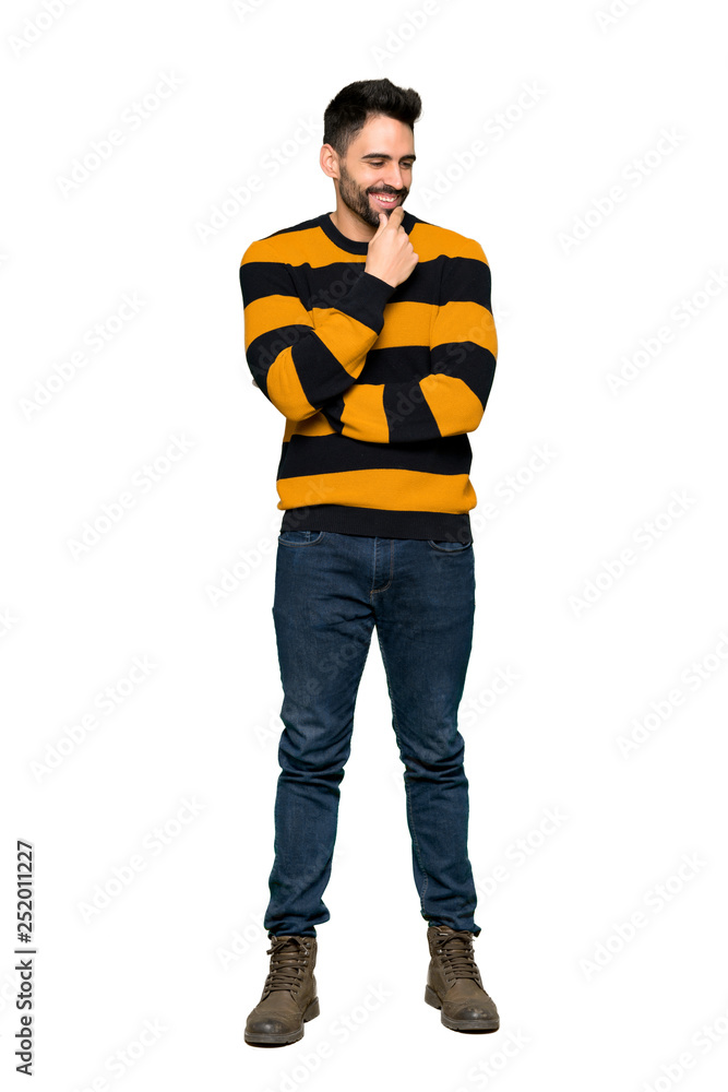 Full-length shot of Handsome man with striped sweater looking to the side with the hand on the chin on isolated white background Full-length shot of Handsome man with striped sweater looking to the side with the hand on the chin on isolated white background