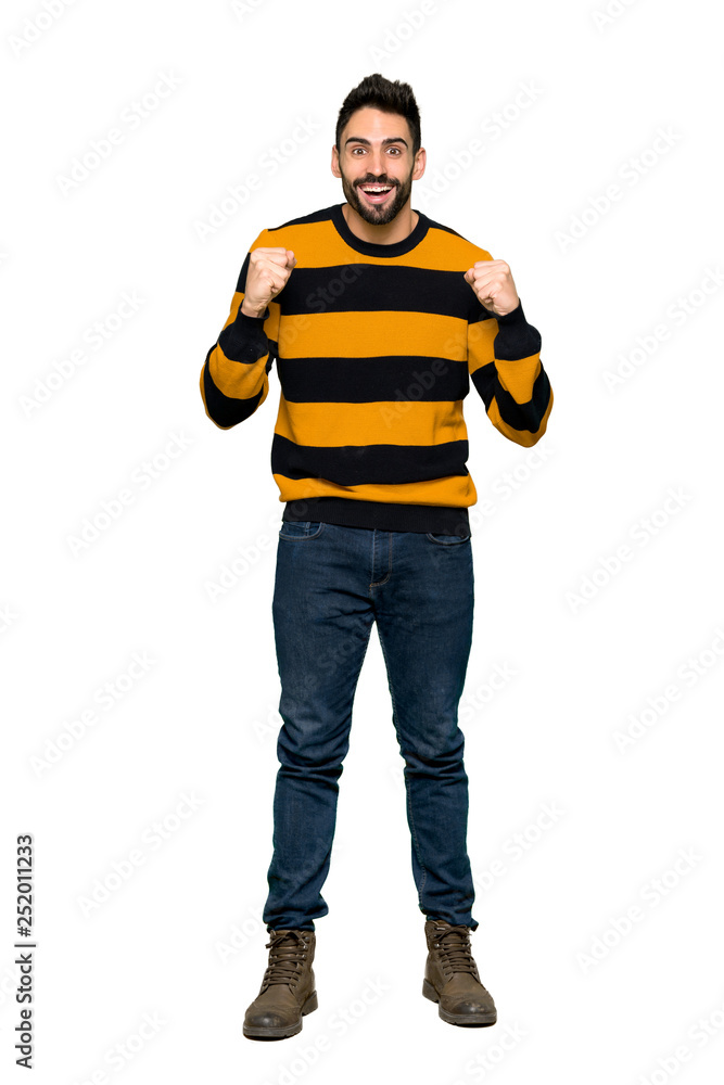 Full-length shot of Handsome man with striped sweater celebrating a victory in winner position on isolated white background Full-length shot of Handsome man with striped sweater celebrating a victory in winner position on isolated white background