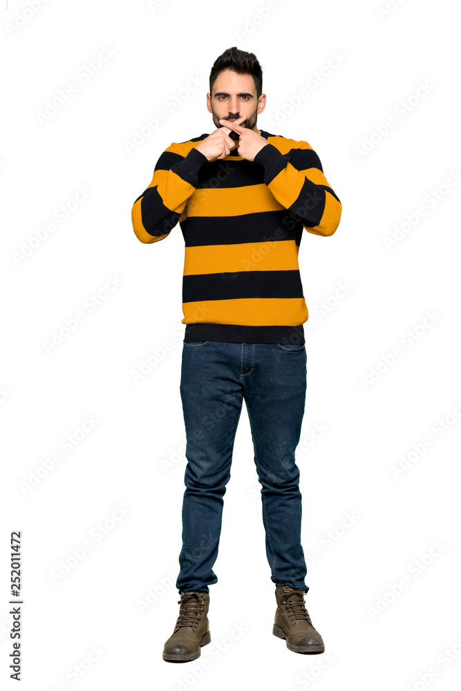 Full-length shot of Handsome man with striped sweater showing a sign of silence gesture on isolated white background Full-length shot of Handsome man with striped sweater showing a sign of silence gesture on isolated white background