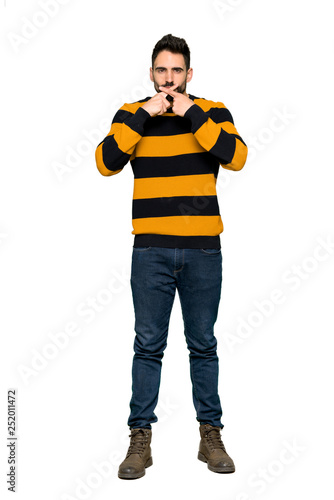 Full-length shot of Handsome man with striped sweater showing a sign of silence gesture on isolated white background