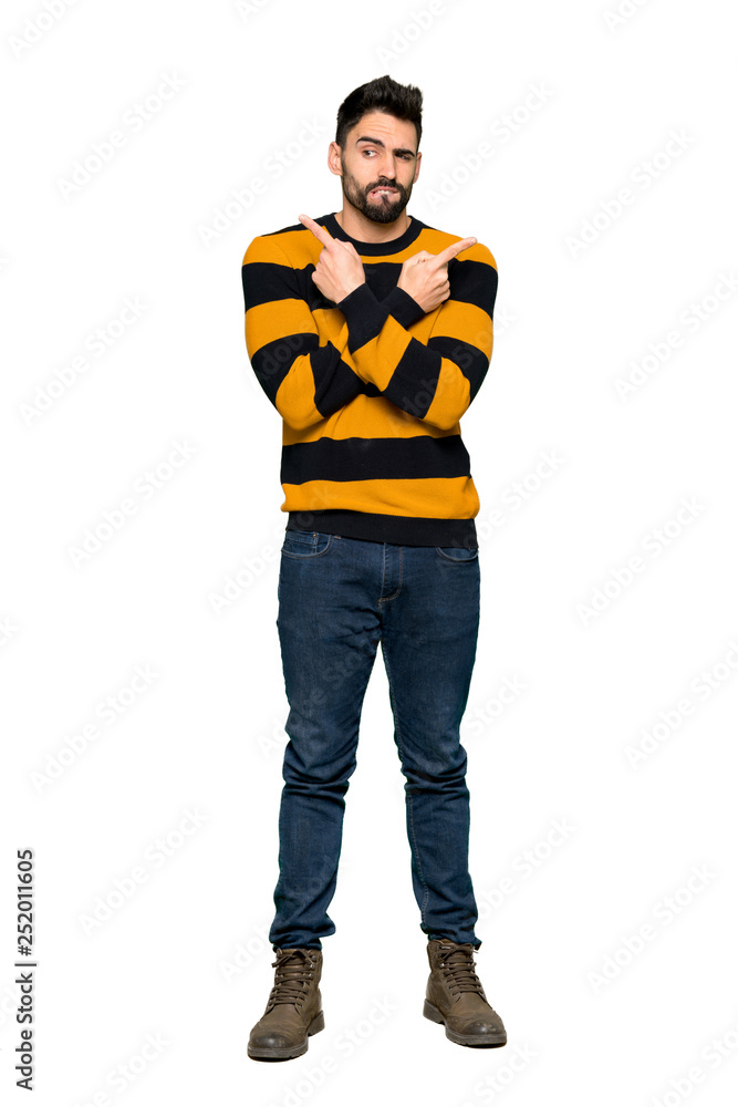 Full-length shot of Handsome man with striped sweater pointing to the laterals having doubts on isolated white background Full-length shot of Handsome man with striped sweater pointing to the laterals having doubts on isolated white background