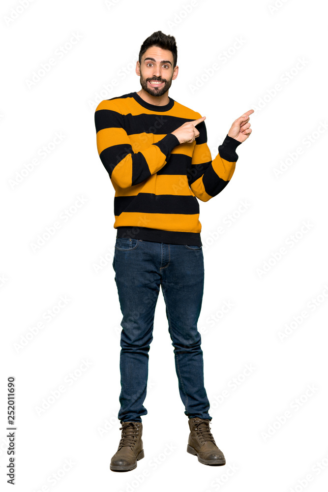 Full-length shot of Handsome man with striped sweater frightened and pointing to the side on isolated white background Full-length shot of Handsome man with striped sweater frightened and pointing to the side on isolated white background