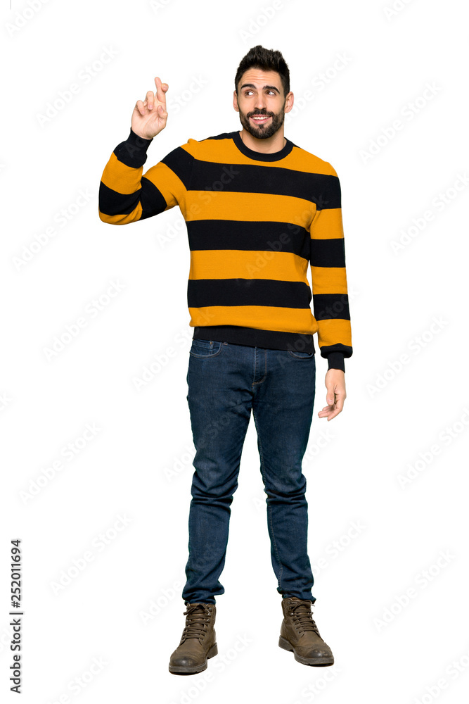 Full-length shot of Handsome man with striped sweater with fingers crossing and wishing the best on isolated white background Full-length shot of Handsome man with striped sweater with fingers crossing and wishing the best on isolated white background