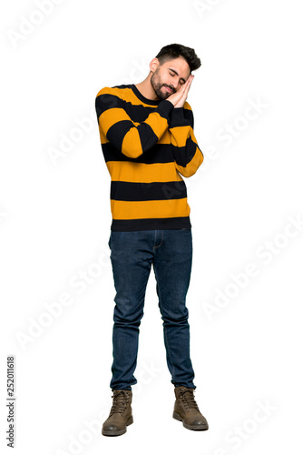Full-length shot of Handsome man with striped sweater making sleep gesture in dorable expression on isolated white background