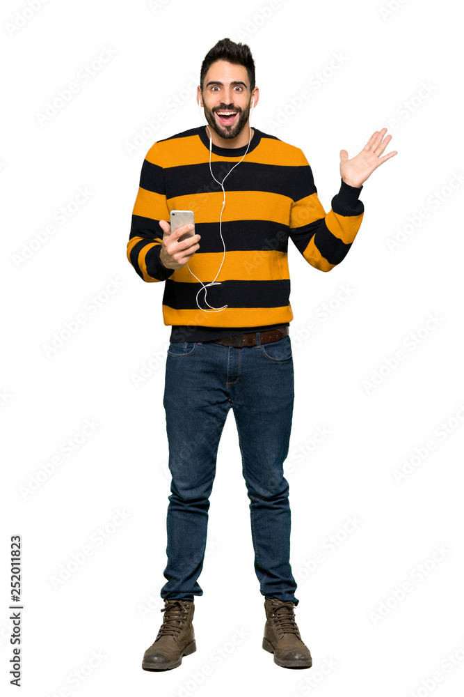 Full-length shot of Handsome man with striped sweater surprised and sending a message on isolated white background Full-length shot of Handsome man with striped sweater surprised and sending a message on isolated white background