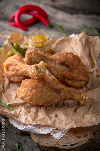 Juicy, crispy fried chicken leg for take away or food delivery on wooden background, rustic style. Fast food 