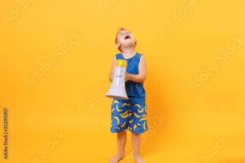 Kid boy 3-4 years old in blue beach summer clothes hold speak in megaphone isolated on bright yellow orange background children studio portrait. People childhood lifestyle concept Mock up copy space.