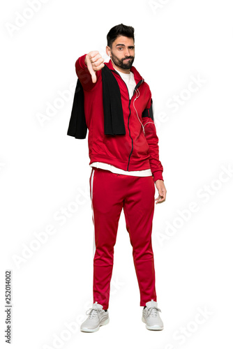 Full-length shot of Handsome sportman showing thumb down sign with negative expression on isolated white background