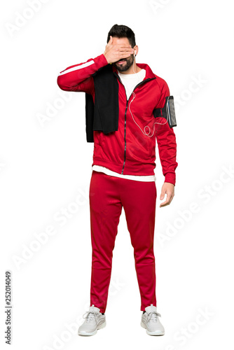 Full-length shot of Handsome sportman covering eyes by hands. Do not want to see something on isolated white background