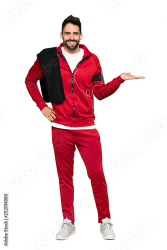Full-length shot of Handsome sportman holding copyspace imaginary on the palm to insert an ad on isolated white background