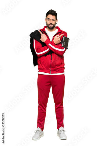 Full-length shot of Handsome sportman pointing to the laterals having doubts on isolated white background