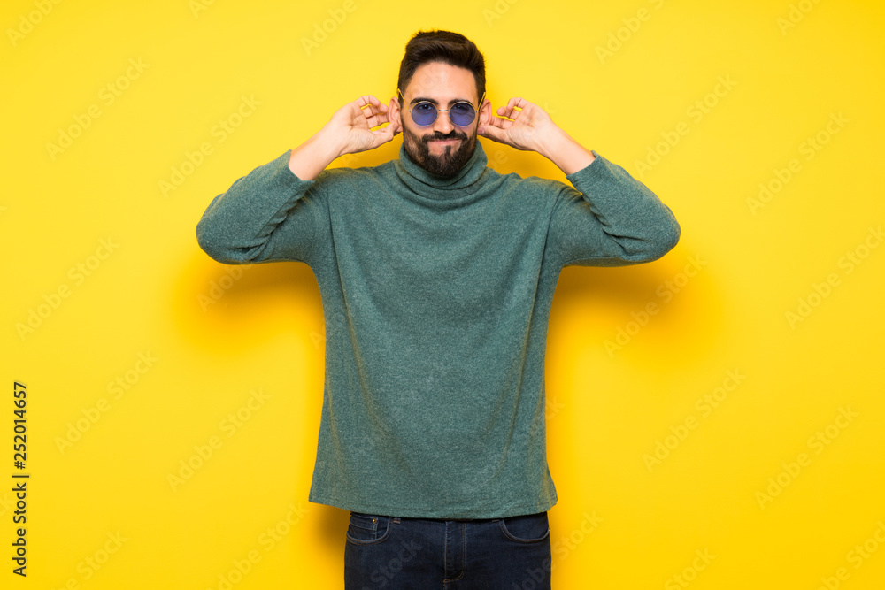 Handsome man with sunglasses covering ears with hands. Frustrated expression Handsome man with sunglasses covering ears with hands. Frustrated expression
