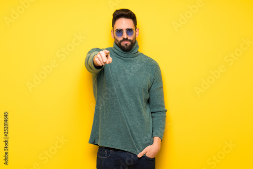 Handsome man with sunglasses frustrated by a bad situation and pointing to the front