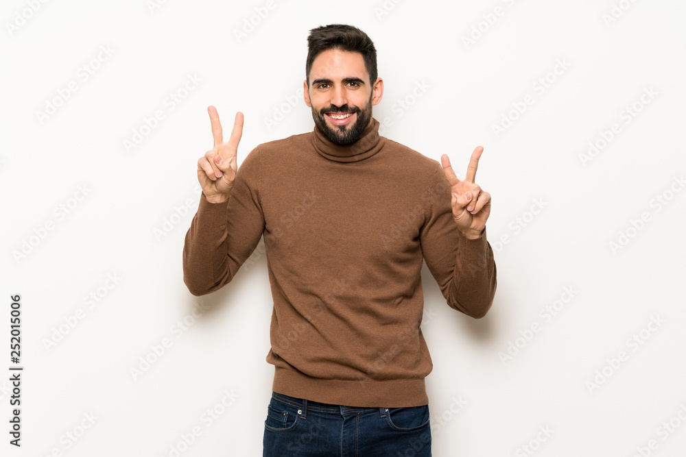 Handsome man over white wall smiling and showing victory sign with both hands Handsome man over white wall smiling and showing victory sign with both hands