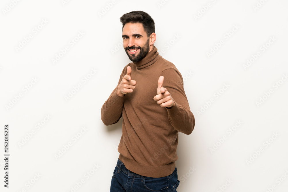 Handsome man over white wall pointing to the front and smiling Handsome man over white wall pointing to the front and smiling