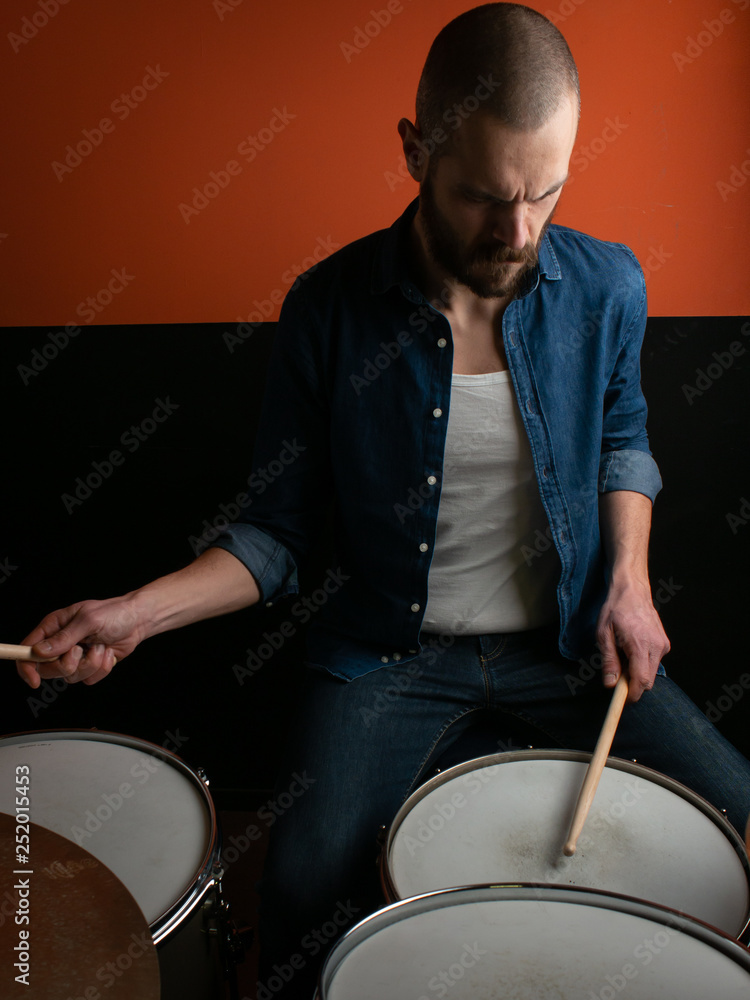 Boy playing drum with jeans shirt and dark background Boy playing drum with jeans shirt and dark background