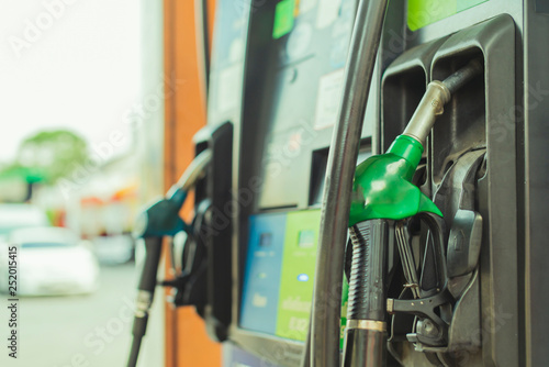 oil Petrol pump filling nozzles in Gas station in a service in color tone image with blur station background