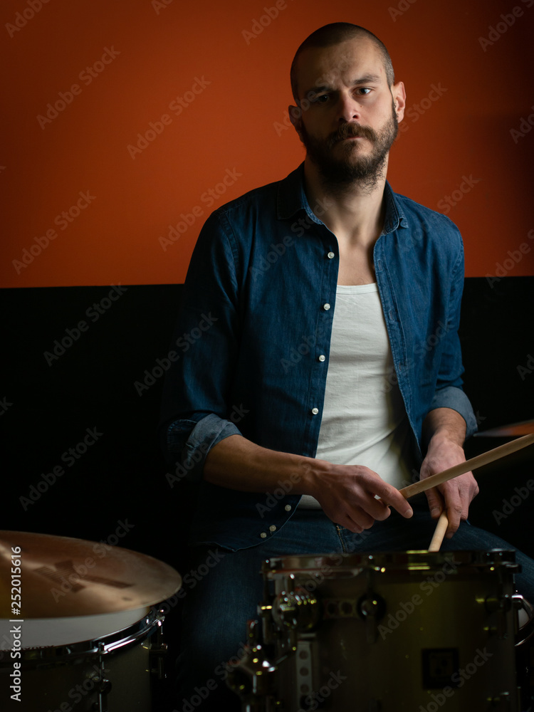 Boy playing drum with jeans shirt and dark background Boy playing drum with jeans shirt and dark background