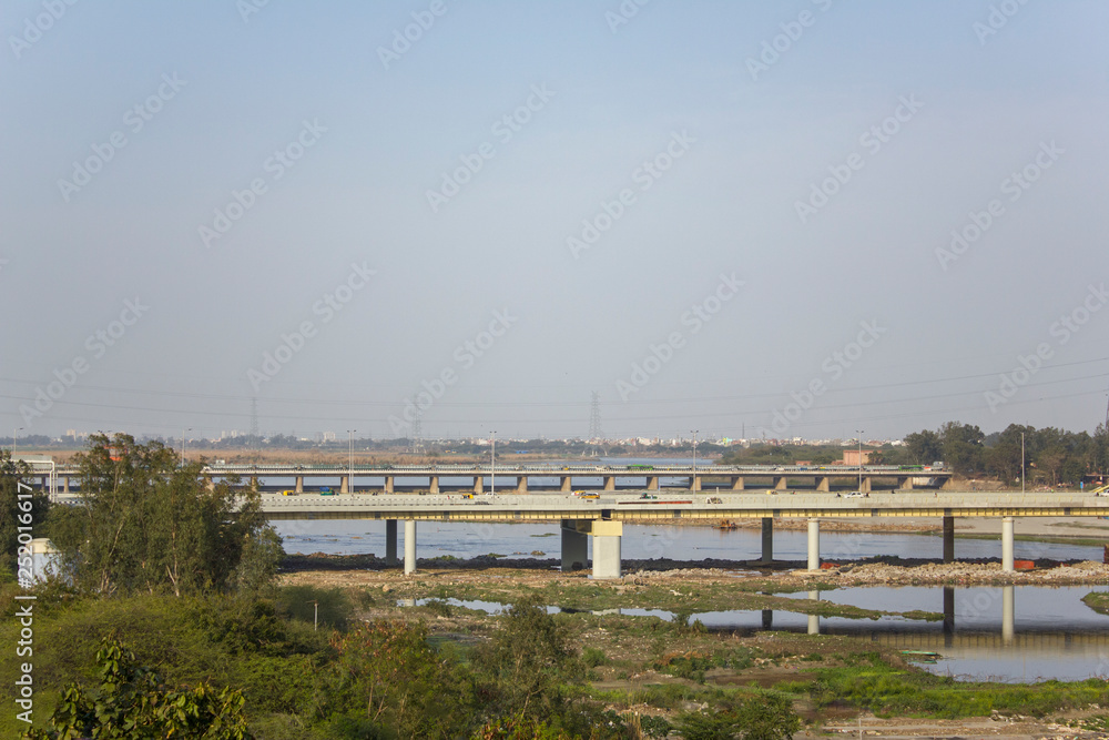 bridge over the river Yamuna with car traffic in the background of the city